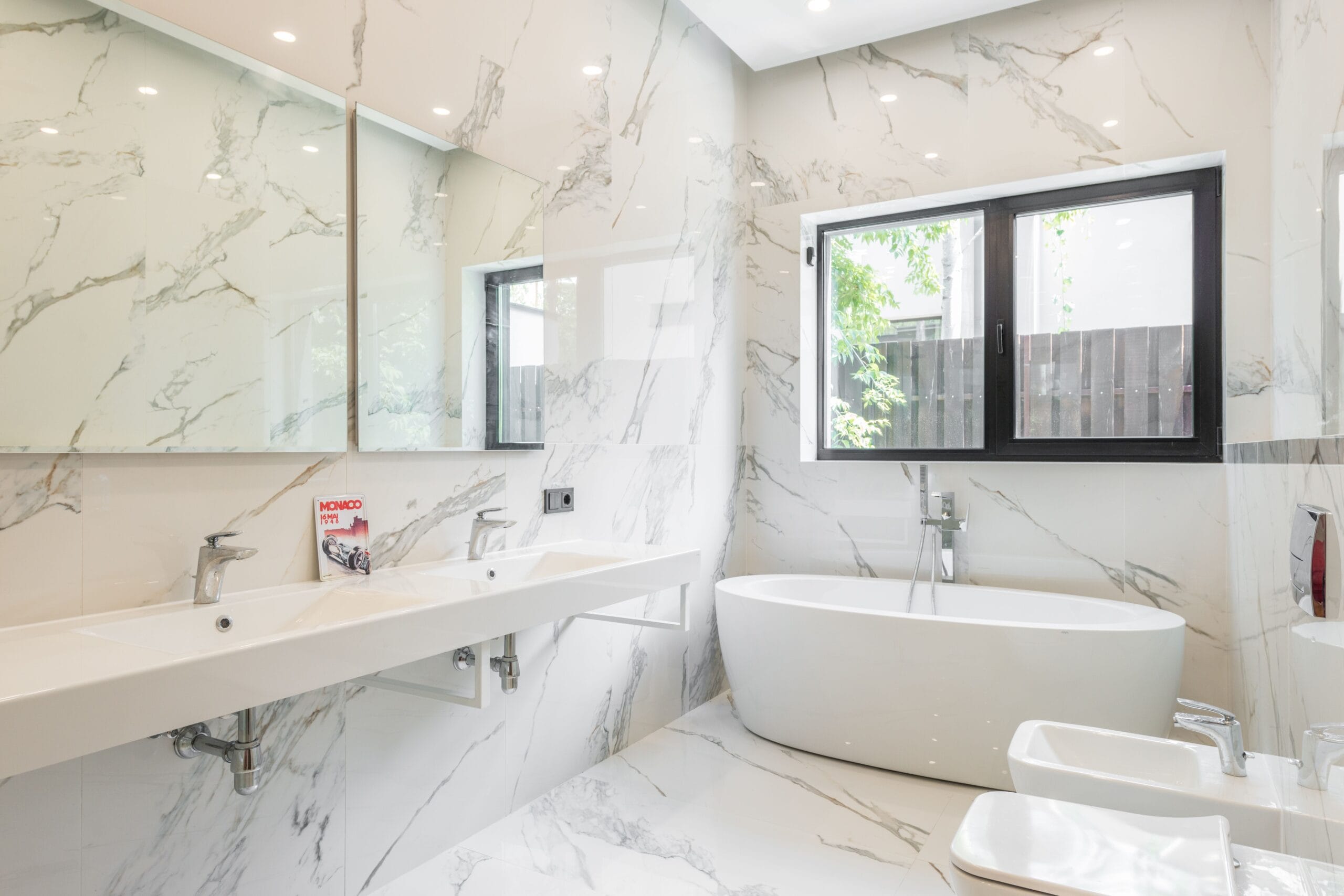 Spacious modern bathroom featuring marble tiles, an elegant bathtub, and stylish fixtures.